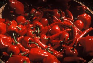 A mixture of fresh red chile pepper types in a basket