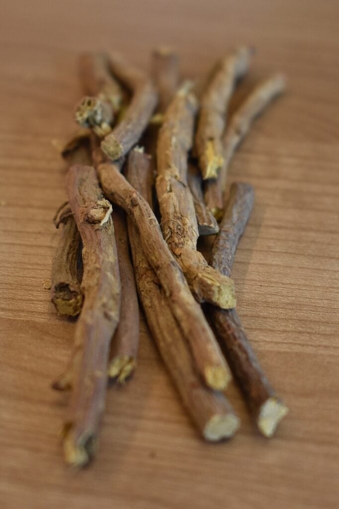 Dried licorice roots on a wooden surface for herbal use.