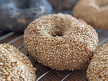 Bagels topped by sesame seeds sitting on a wire rack