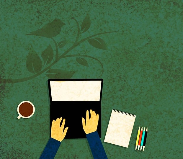 Open laptop with hands typing, with coffee, notebook, and pens nearby