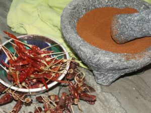 Dried chile peppers and ground chile peppers in a mortar and pestle.