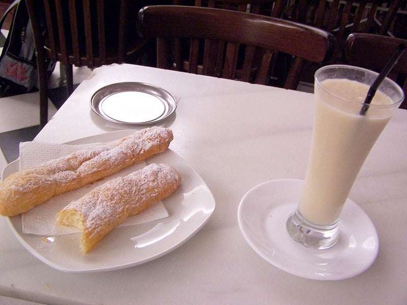 Pastries on a white plate next to a milky glass of horchata