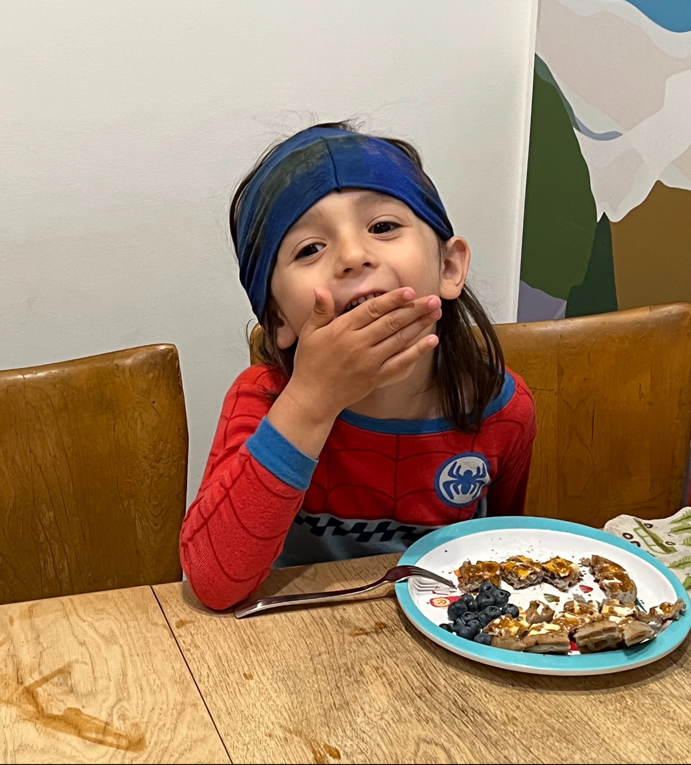 Young boy in a Spiderman costume eating snacks.