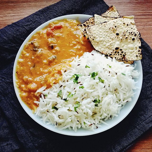 A plate of dal fry tadka, cumin rice, roasted papad on the side