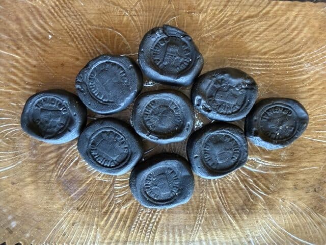 Black licorice candies with embossed logos on a wooden surface.
