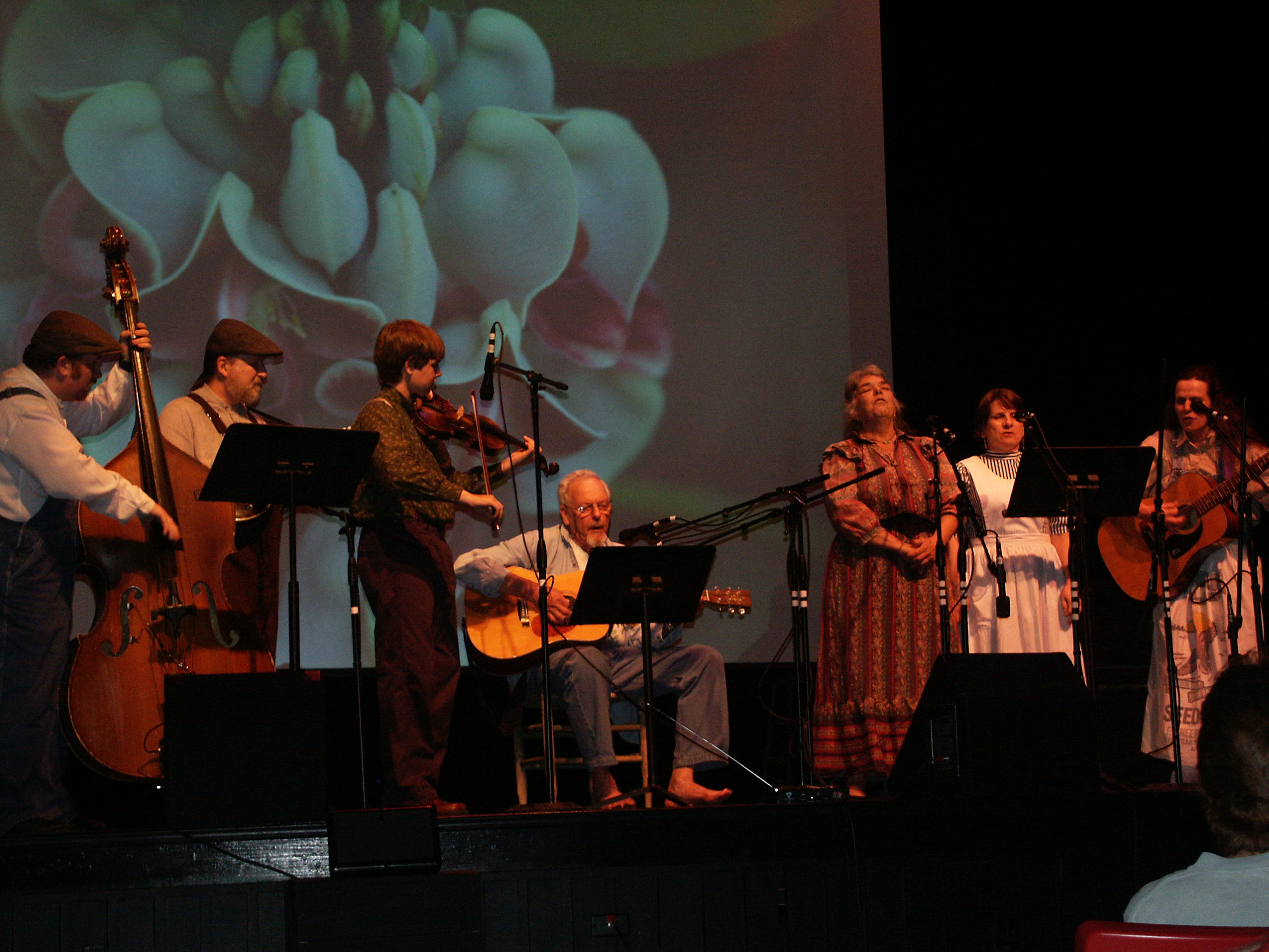 James Duke singing with Ozark Folk Center musicians with Steven Foster's photos showing in the background