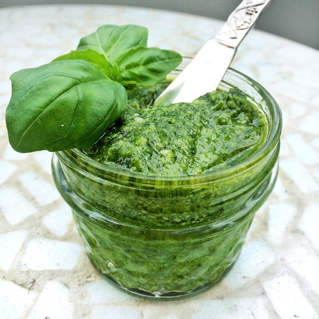 Small glass jar of green basil pesto