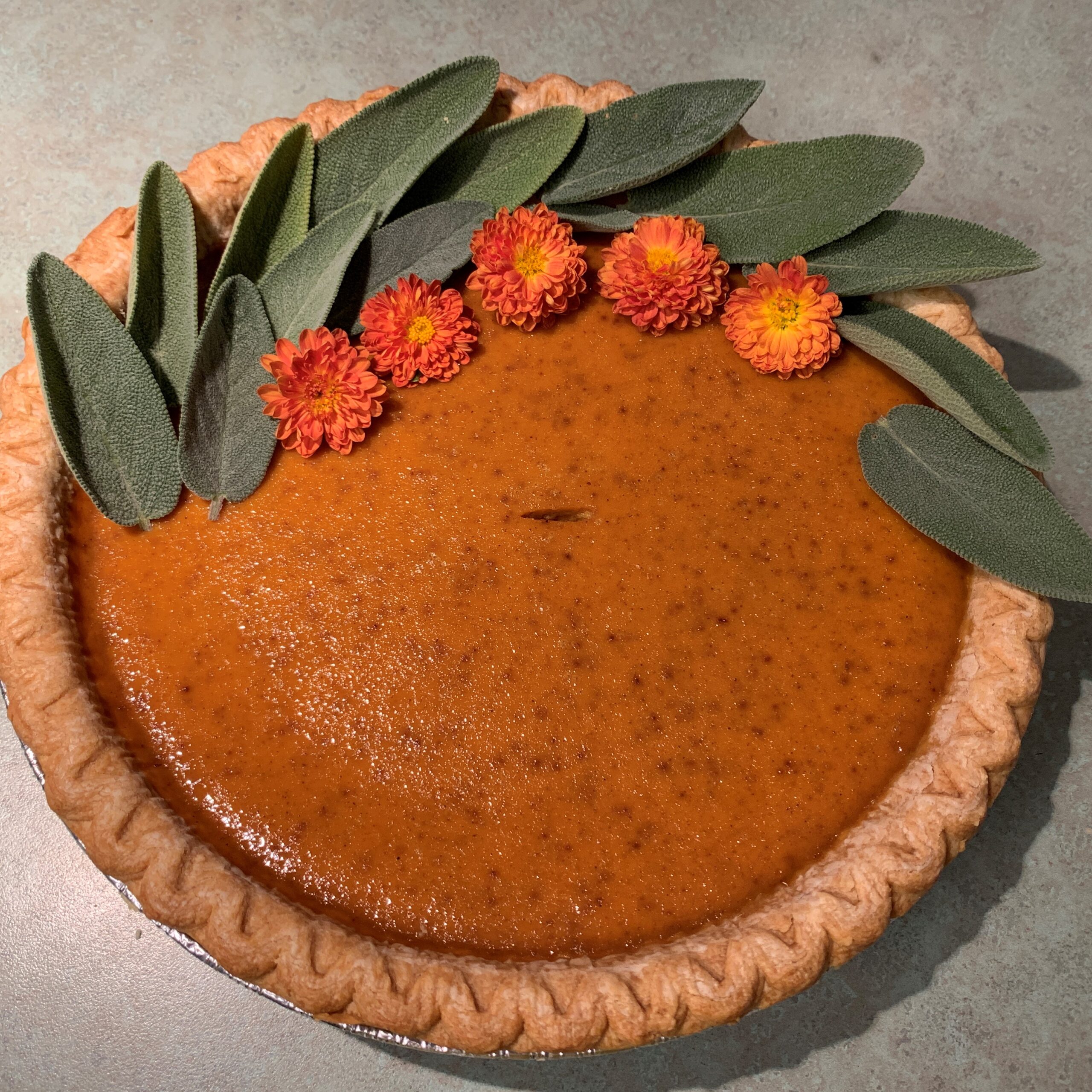 Pumpkin pie with sage leaves and marigold flowers